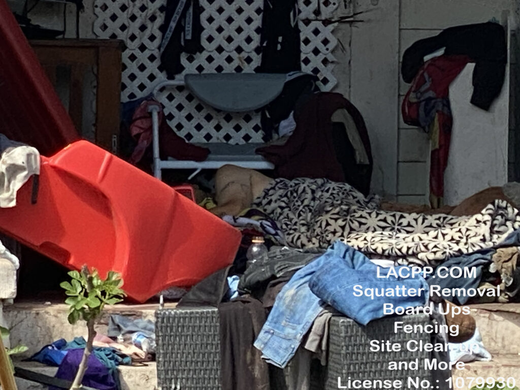 Unauthorized occupant sleeping on the front porch of a fire-damaged property in Los Angeles before property securing, board-up, and cleanup services were performed.