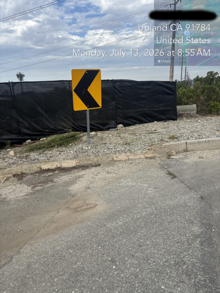 Repaired black privacy screening along a commercial property fence following code-violation cleanup.